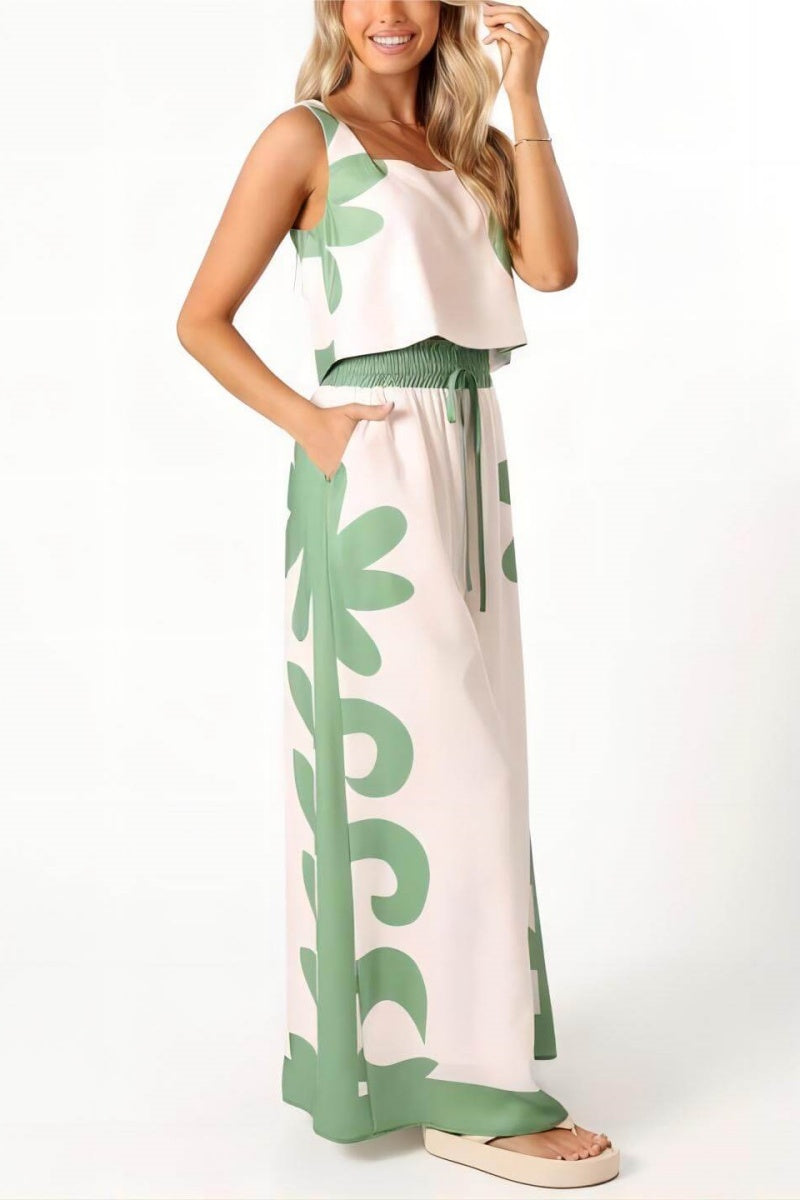 White - A woman wearing a white two-piece summer set featuring a cropped square-neck top and high-waisted wide-leg trousers, both adorned with a bold green abstract botanical print.