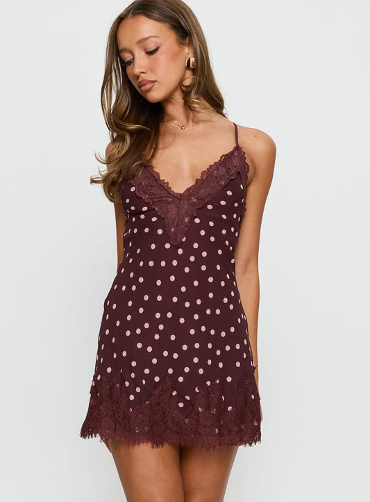 Women's burgundy mini slip dress featuring a light pink polka dot print, delicate lace trim at the V-neckline and hem, and thin spaghetti straps.