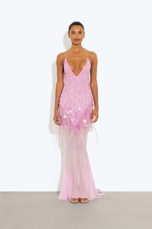 Pink - A model wearing a women's sheer pink maxi dress featuring a plunging V-neckline, delicate straps, and large sequin embellishments cascading down the bodice.
