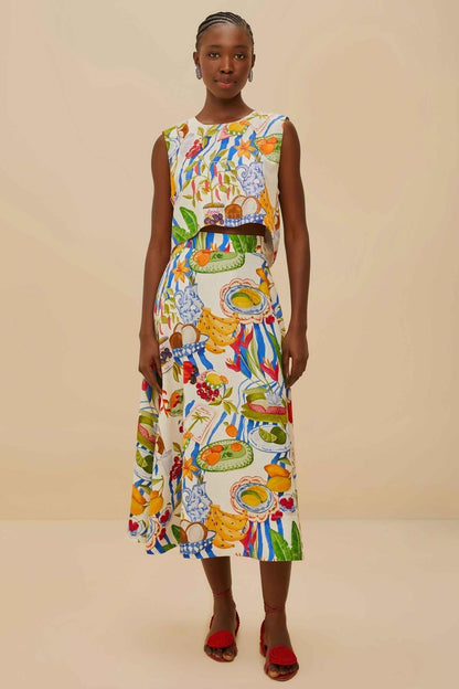 Colorful - Woman wearing a vibrant two-piece co-ord set featuring a sleeveless crop top and high-waisted A-line midi skirt, adorned with a colourful tropical fruit and plate print.