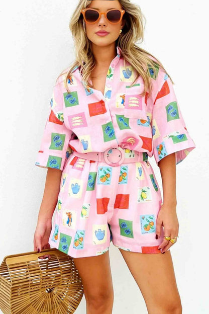 Pink - Women's pink short-sleeve belted playsuit featuring a colourful Mediterranean novelty print with oranges and vases, styled with sunglasses and a bamboo bag.