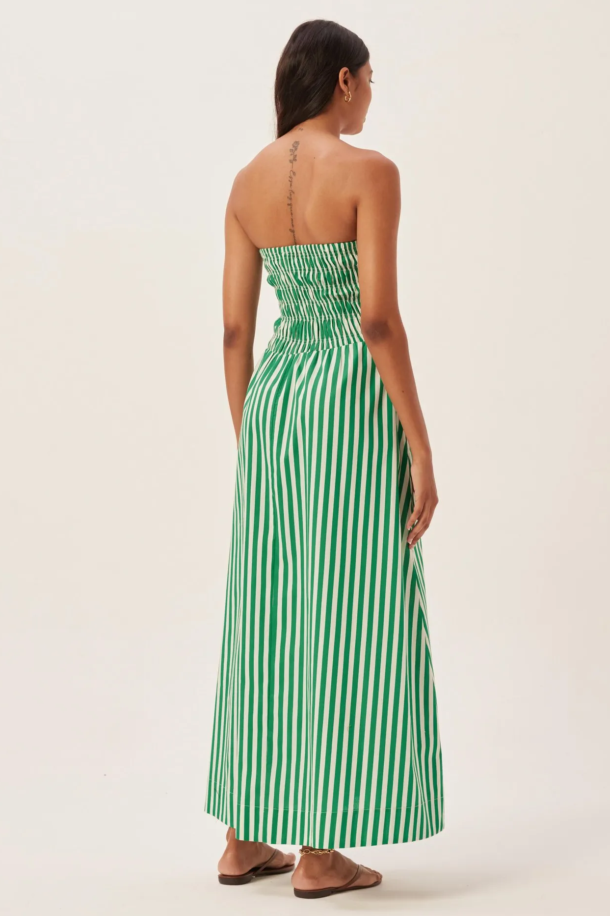 Green - Women's strapless maxi dress featuring a shirred bandeau bodice and bold green and white vertical stripes, styled with a woven straw tote bag.