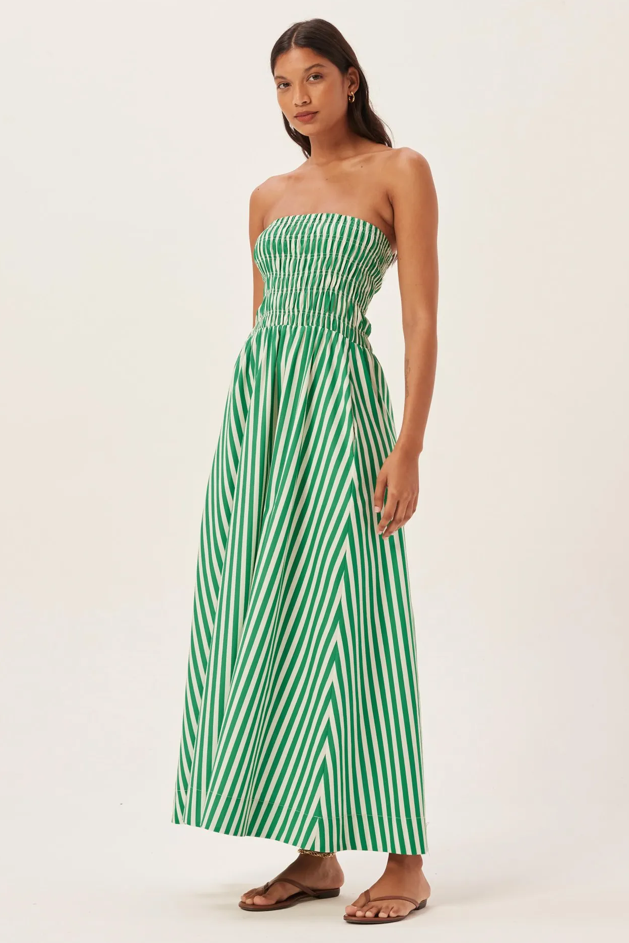 Green - Women's strapless maxi dress featuring a shirred bandeau bodice and bold green and white vertical stripes, styled with a woven straw tote bag.