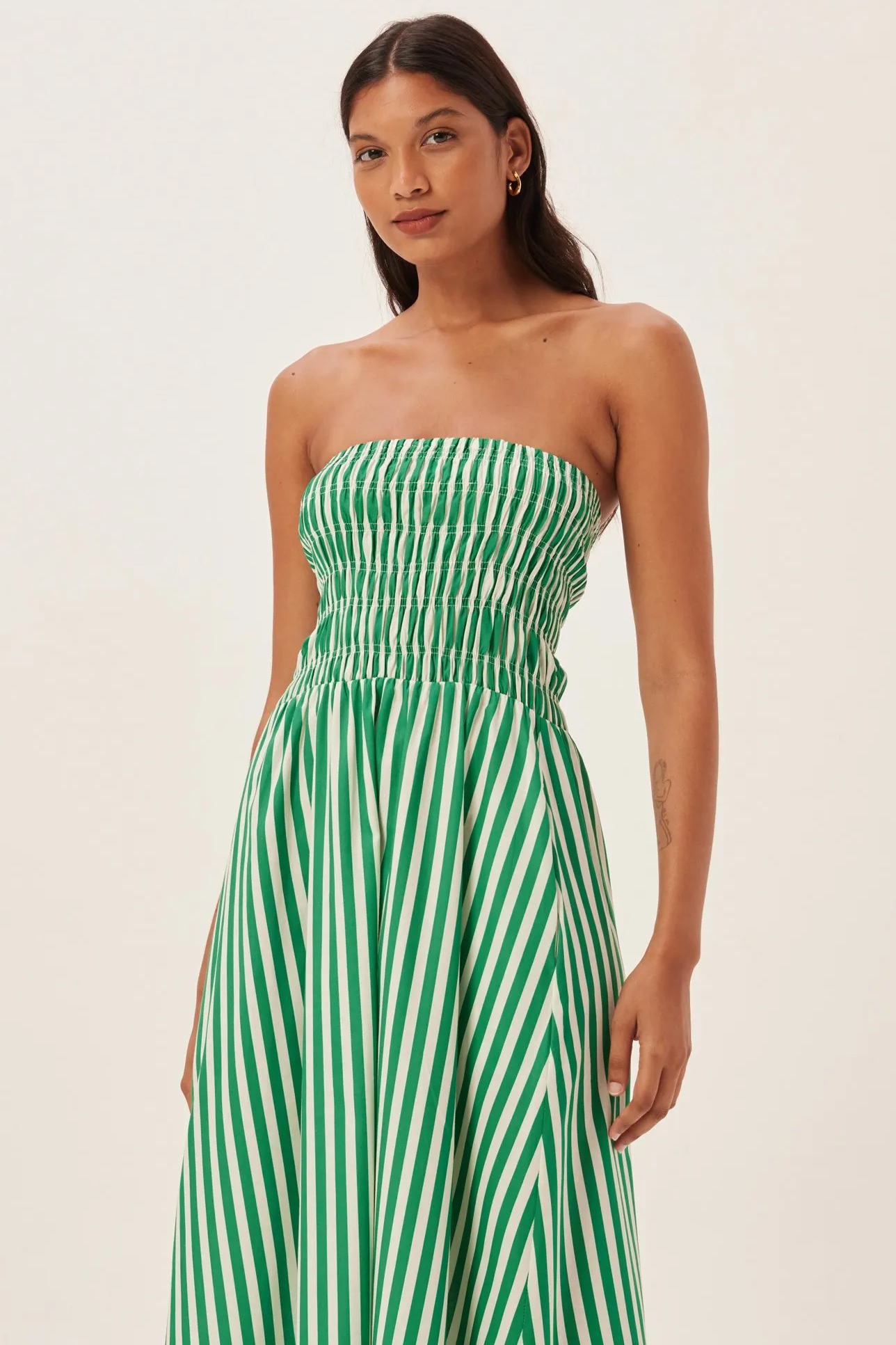Green - Women's strapless maxi dress featuring a shirred bandeau bodice and bold green and white vertical stripes, styled with a woven straw tote bag.