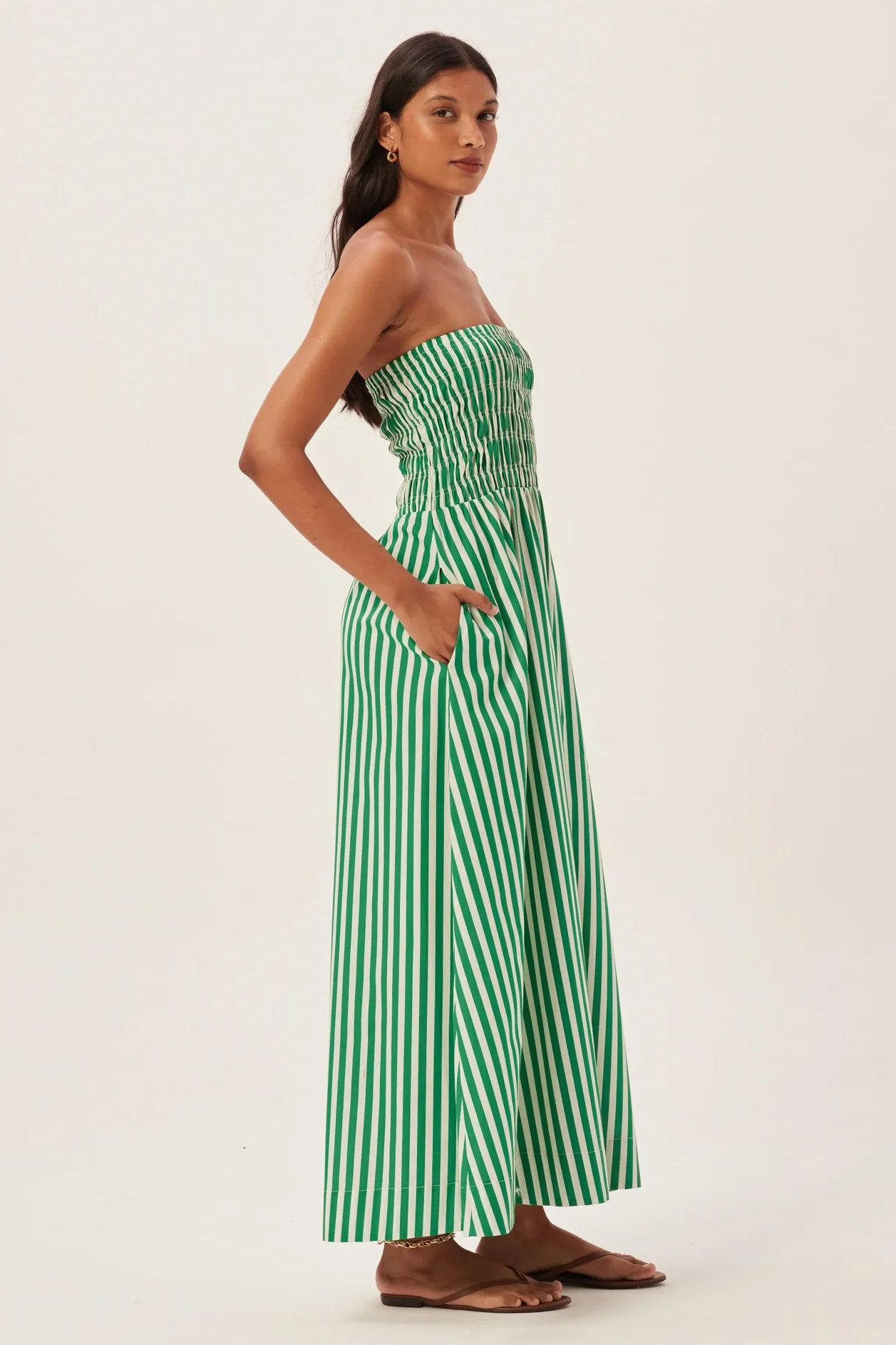 Green - Women's strapless maxi dress featuring a shirred bandeau bodice and bold green and white vertical stripes, styled with a woven straw tote bag.