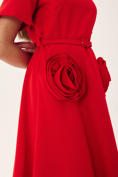 Red - A woman wearing a bright red, short-sleeved midi dress featuring a notched V-neckline, a thin waist belt, and two large 3D rosette embellishments on the A-line skirt.