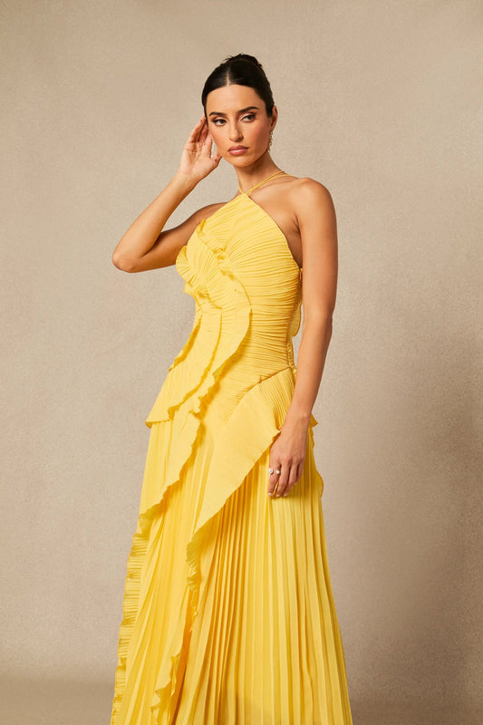 XXL - A woman modelling a bright yellow, floor-length plissé maxi dress featuring a halter neckline, fitted bodice, and cascading ruffled tiers.