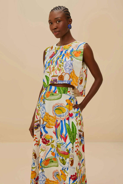 Colorful - Woman wearing a vibrant two-piece co-ord set featuring a sleeveless crop top and high-waisted A-line midi skirt, adorned with a colourful tropical fruit and plate print.