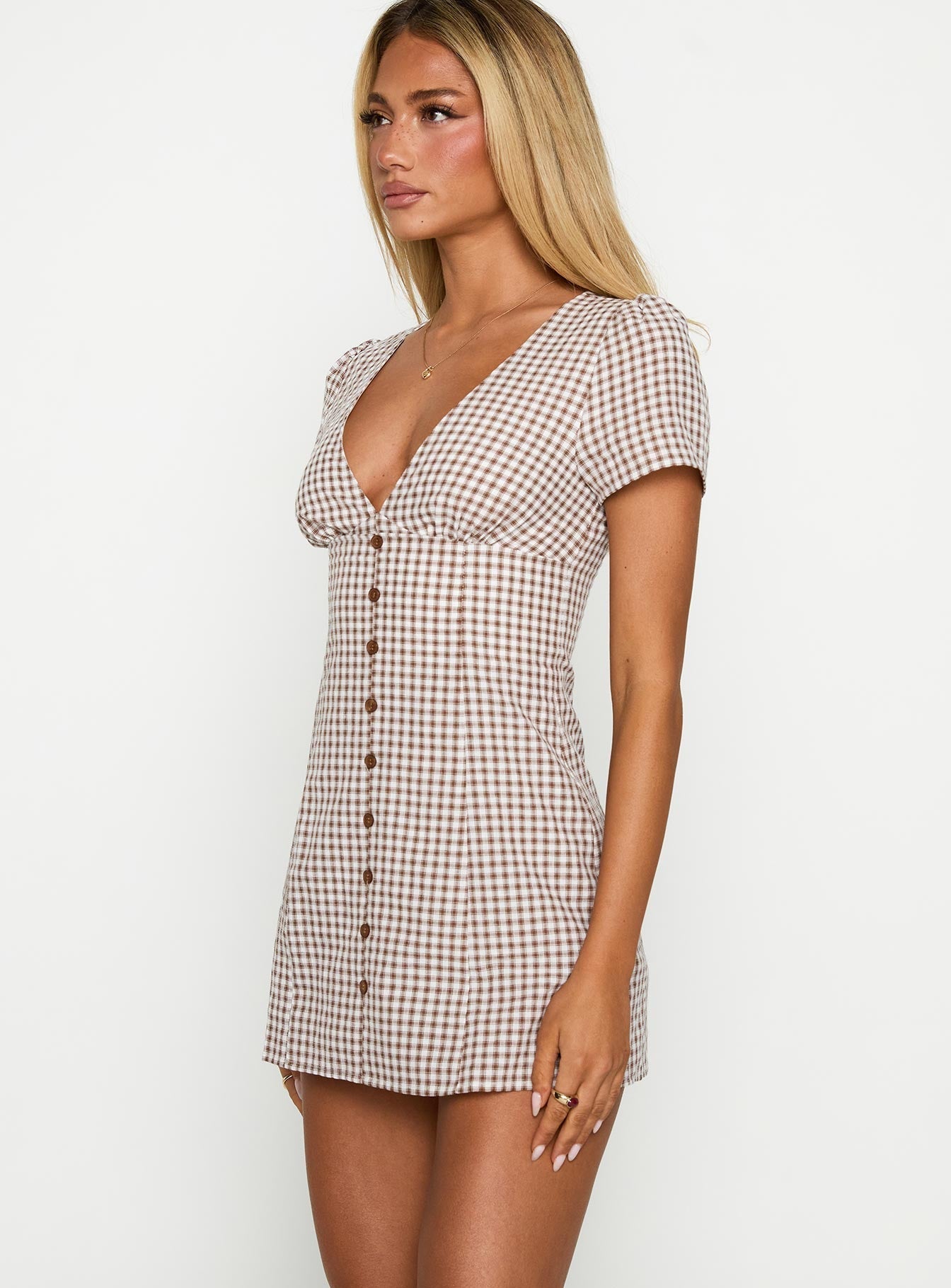 Women's short-sleeve mini dress featuring a brown and white gingham check pattern, a deep V-neckline, and a functional button-down front.