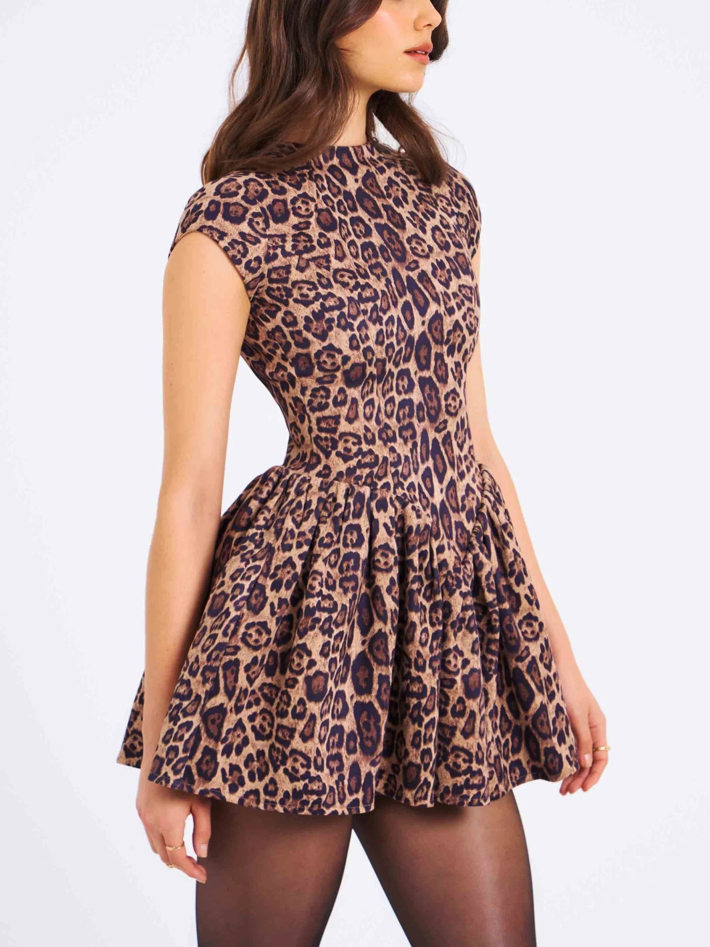 Women's high-neck, cap-sleeve mini dress featuring a fitted bodice, a gathered drop-waist skirt, and an all-over leopard print.