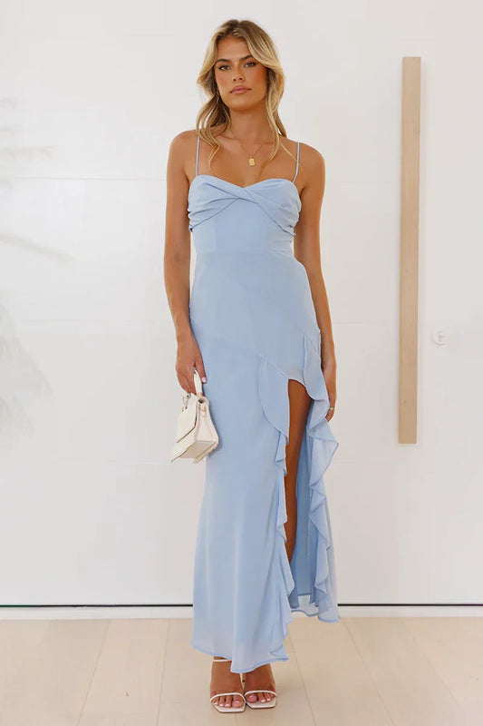 A woman modelling a light blue maxi dress featuring thin straps, a twisted sweetheart bust, and a high side slit trimmed with cascading ruffles.