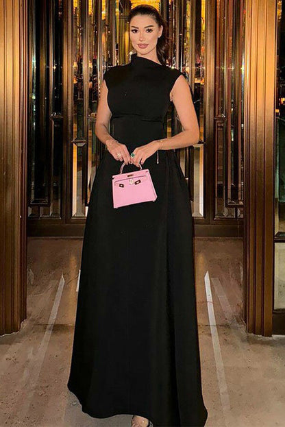 Woman wearing an elegant white sleeveless maxi dress with a high neckline and a structured, voluminous skirt, standing on outdoor brick steps at night.