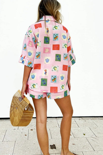 Pink - Women's pink short-sleeve belted playsuit featuring a colourful Mediterranean novelty print with oranges and vases, styled with sunglasses and a bamboo bag.
