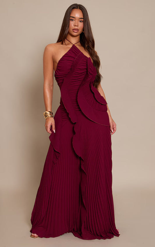 Women's elegant halter neck maxi dress featuring a tightly ruched bodice, a prominent cascading ruffle down the front, and a flowing, finely pleated floor-length skirt.