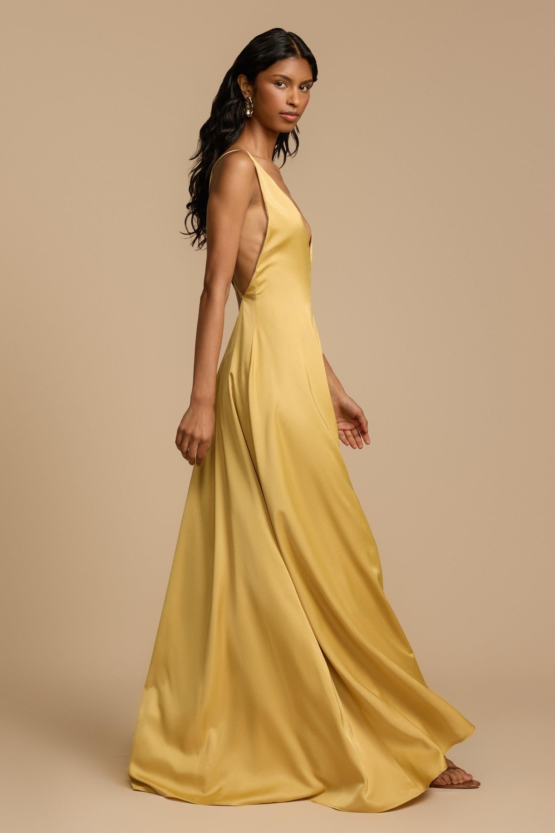 Gold - A woman modelling an elegant, floor-length golden yellow sleeveless maxi dress featuring a deep plunge V-neckline and a smooth, flowing skirt with a subtle satin-like sheen.