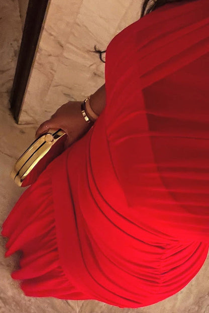 Red - A woman modelling a vibrant red sleeveless maxi dress with a sheer high neckline, ruched bodice, and flowing skirt in an elegant bar setting.