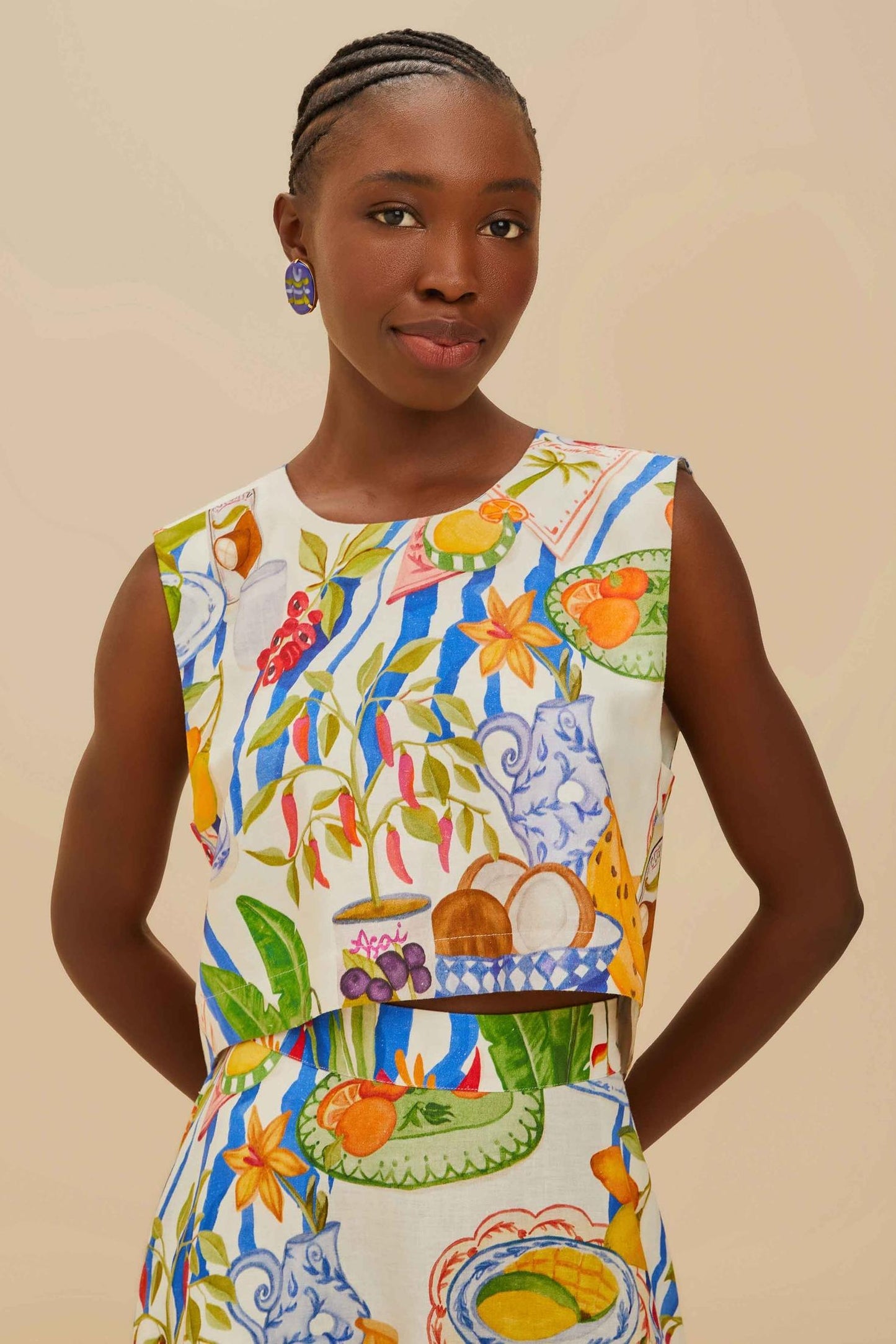 Colorful - Woman wearing a vibrant two-piece co-ord set featuring a sleeveless crop top and high-waisted A-line midi skirt, adorned with a colourful tropical fruit and plate print.