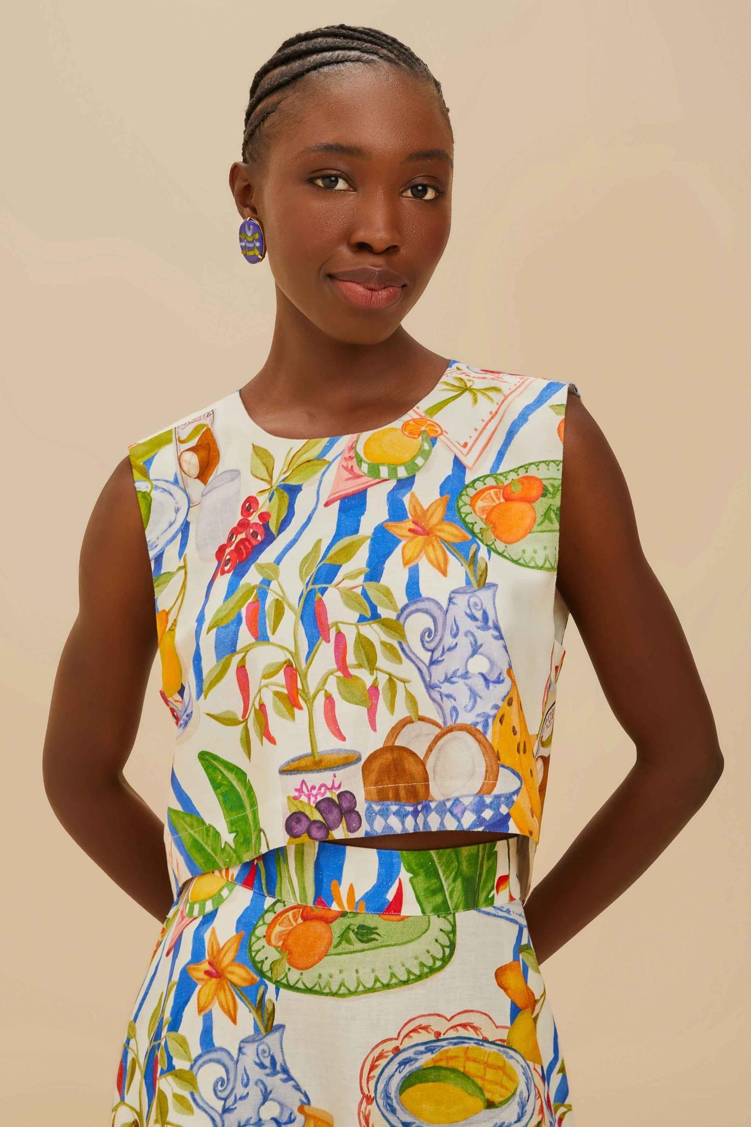 Colorful - Woman wearing a vibrant two-piece co-ord set featuring a sleeveless crop top and high-waisted A-line midi skirt, adorned with a colourful tropical fruit and plate print.