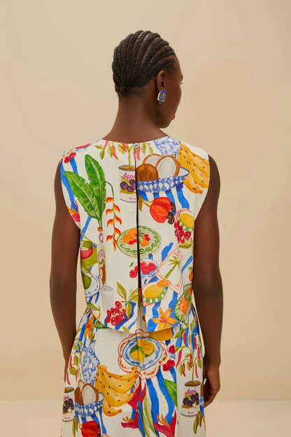 Colorful - Woman wearing a vibrant two-piece co-ord set featuring a sleeveless crop top and high-waisted A-line midi skirt, adorned with a colourful tropical fruit and plate print.
