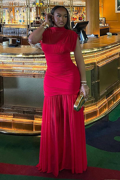 Red - A woman modelling a vibrant red sleeveless maxi dress with a sheer high neckline, ruched bodice, and flowing skirt in an elegant bar setting.