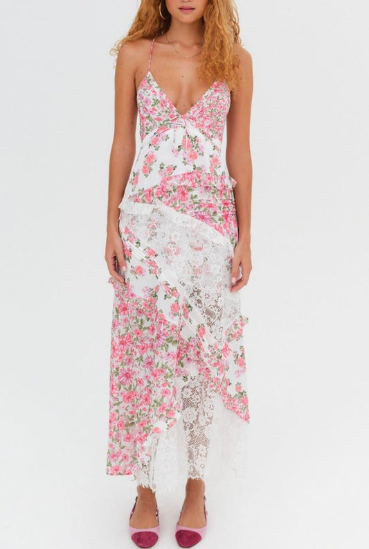 Women's white maxi dress featuring a pink floral print, plunging V-neckline, and asymmetrical sheer lace panels throughout the tiered skirt.