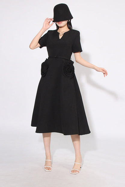 Black - A woman wearing a bright red, short-sleeved midi dress featuring a notched V-neckline, a thin waist belt, and two large 3D rosette embellishments on the A-line skirt.