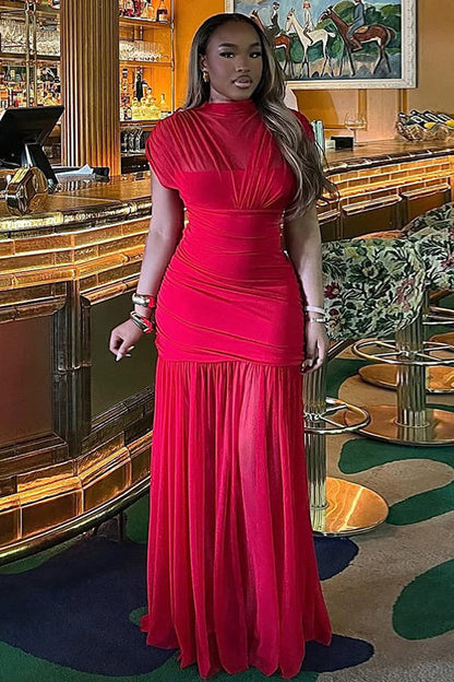 Red - A woman modelling a vibrant red sleeveless maxi dress with a sheer high neckline, ruched bodice, and flowing skirt in an elegant bar setting.