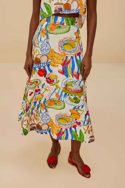Colorful - Woman wearing a vibrant two-piece co-ord set featuring a sleeveless crop top and high-waisted A-line midi skirt, adorned with a colourful tropical fruit and plate print.