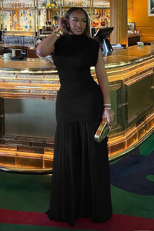 Black - A woman modelling a vibrant red sleeveless maxi dress with a sheer high neckline, ruched bodice, and flowing skirt in an elegant bar setting.