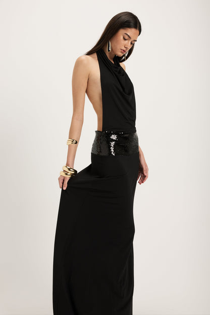 XL - Women's dark red maxi dress featuring a draped cowl halter neckline, an open back, and a wide sequin-embellished band at the waist, falling to a floor-length hem.