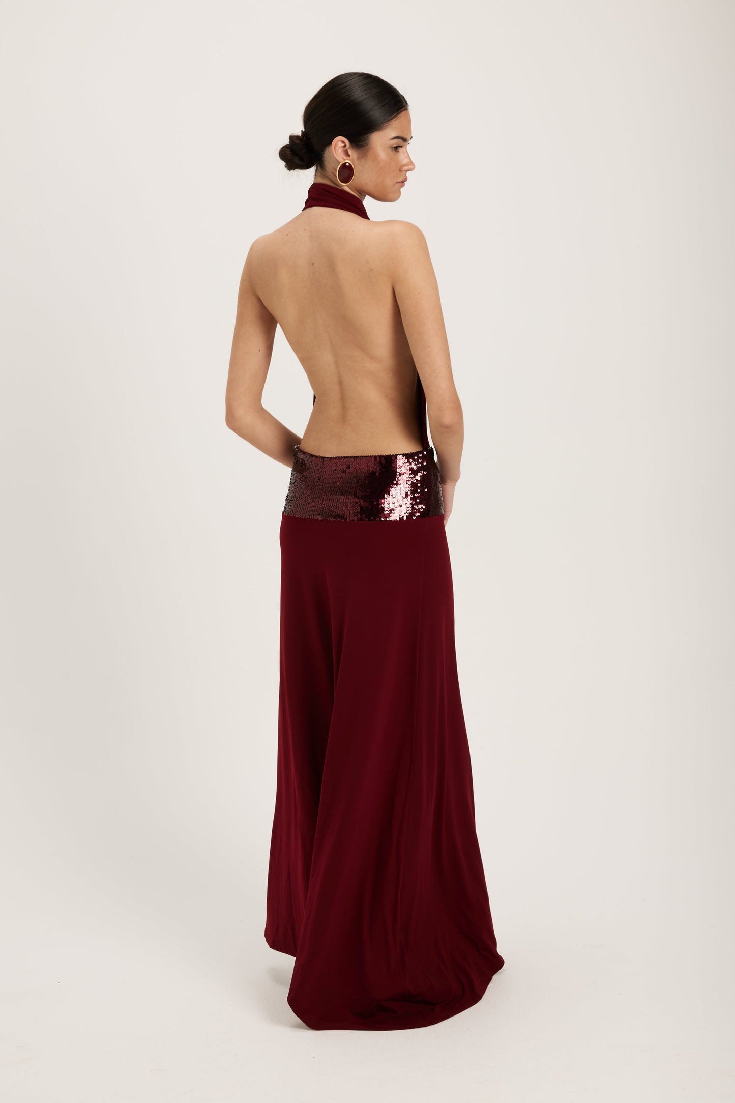 XL - Women's dark red maxi dress featuring a draped cowl halter neckline, an open back, and a wide sequin-embellished band at the waist, falling to a floor-length hem.