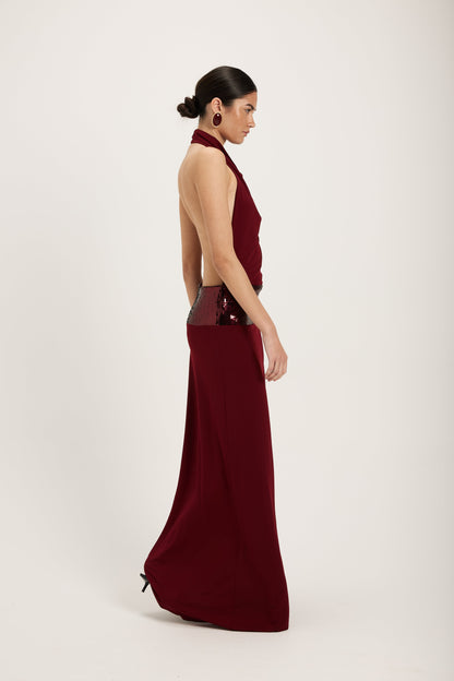 XL - Women's dark red maxi dress featuring a draped cowl halter neckline, an open back, and a wide sequin-embellished band at the waist, falling to a floor-length hem.
