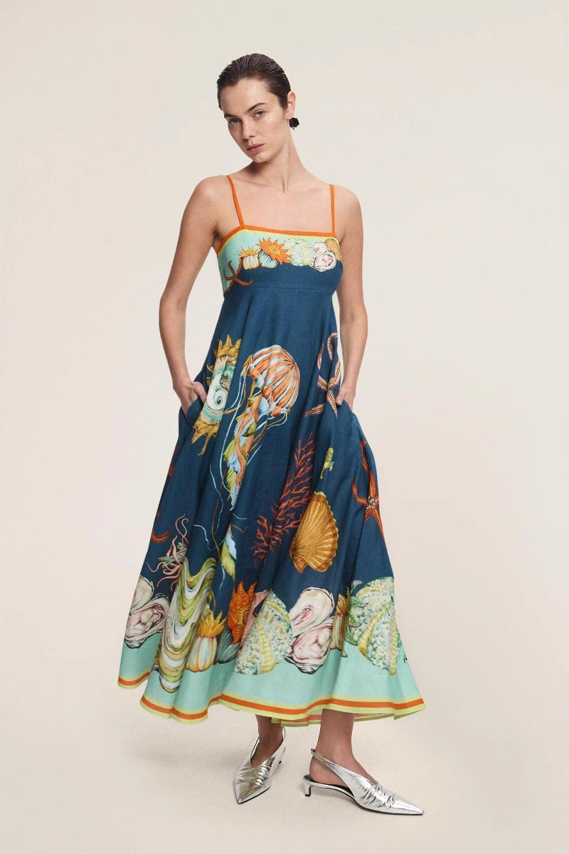 Women's elegant midi dress featuring a vibrant, large-scale marine and seashell print, styled with delicate spaghetti straps, a square neckline, and a flared A-line skirt with pockets.