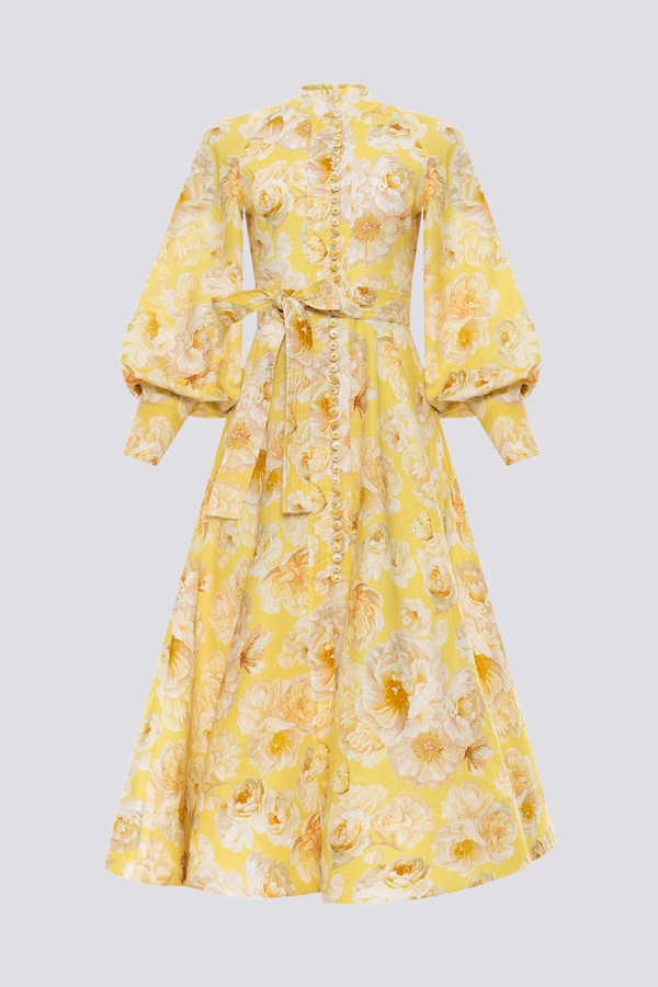 Yellow - A woman wearing a yellow maxi dress with a large white floral print, featuring long balloon sleeves, a button-down front, and a tie waist.