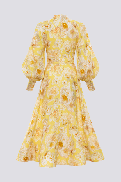 Yellow - A woman wearing a yellow maxi dress with a large white floral print, featuring long balloon sleeves, a button-down front, and a tie waist.
