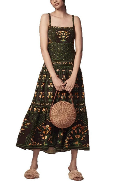 Green - Woman wearing a dark green and black maxi dress featuring a square neckline, wide straps, a tiered skirt, and an intricate botanical floral border print.