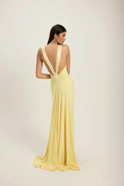 Yellow - A woman modeling a pale yellow, floor-length sleeveless gown featuring a deep plunging V-neckline with a smooth, contrasting trim detail.