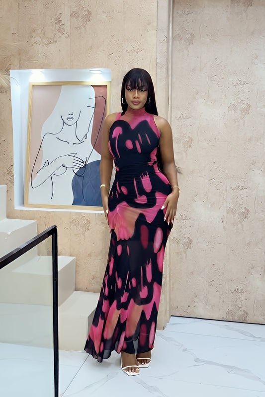 Woman wearing a sleeveless, high-neck maxi dress featuring a bold pink and black abstract print with ruched waist detailing.