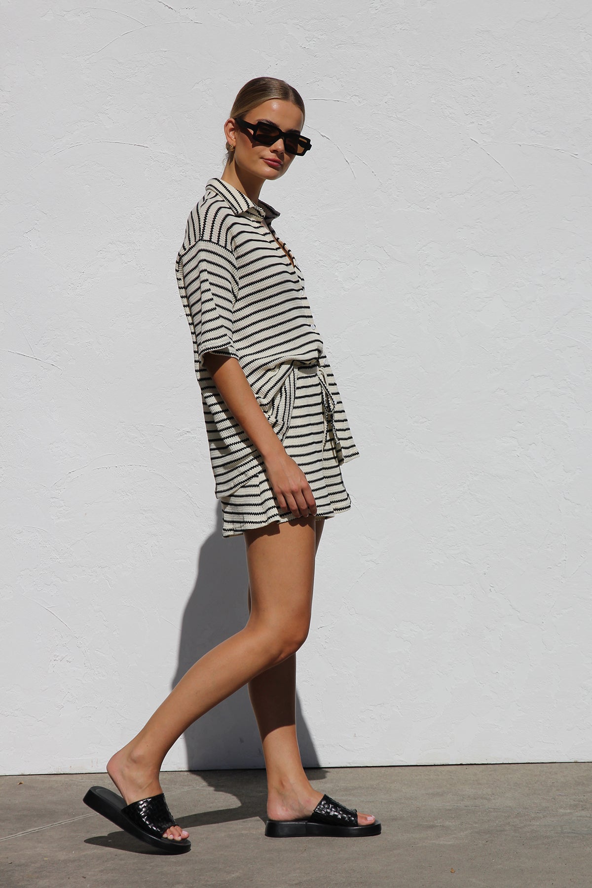 Black - A woman wearing a relaxed-fit, short-sleeve button-down shirt and matching shorts featuring a textured horizontal stripe pattern.