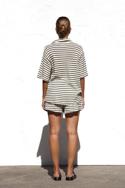 Black - A woman wearing a relaxed-fit, short-sleeve button-down shirt and matching shorts featuring a textured horizontal stripe pattern.