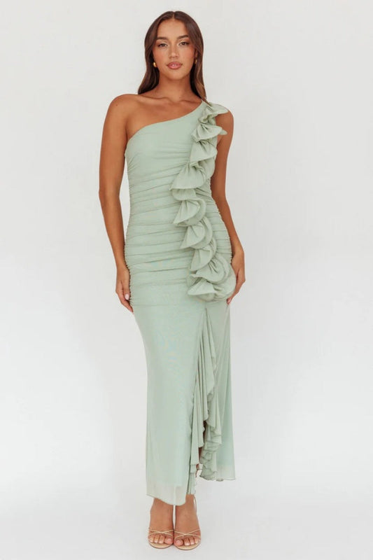 A woman modelling an elegant pale green one-shoulder maxi dress featuring all-over ruching, a dramatic cascading ruffle down the front, and a leg slit.