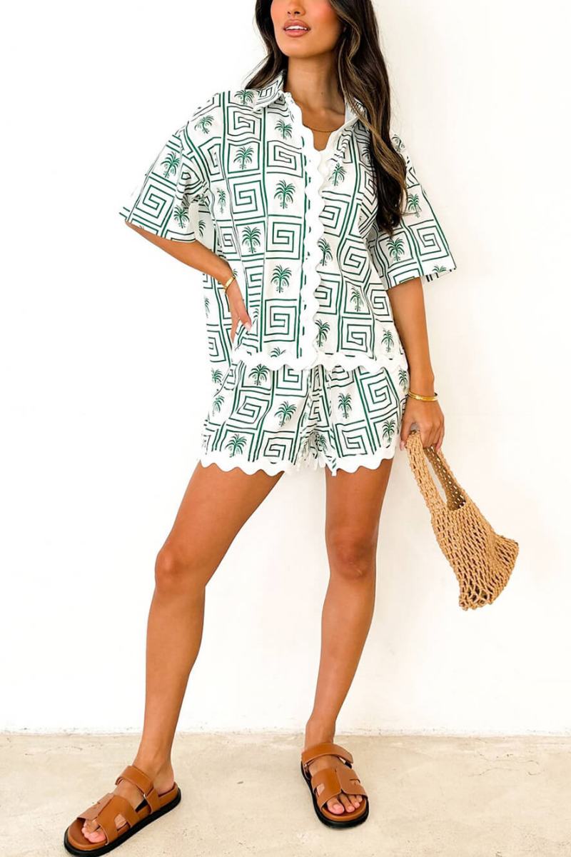 Green - Model wearing a pink and red geometric palm print matching co-ord set featuring a short-sleeve button-up shirt and shorts with white scalloped trim.