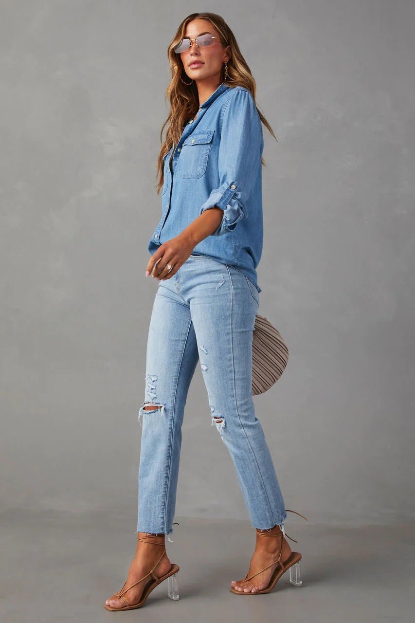 Blue - Women's relaxed-fit chambray button-down shirt featuring dual chest pockets and rolled sleeves, styled with denim jeans.