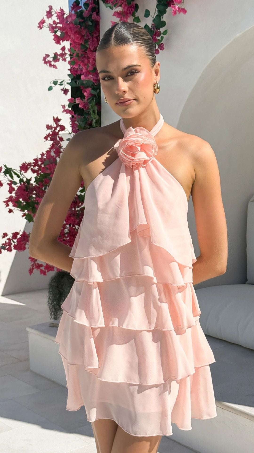 Pink - Women's yellow sleeveless mini dress featuring a halter neckline with a rosette detail and multiple flowing, ruffled tiers in a semi-sheer fabric.