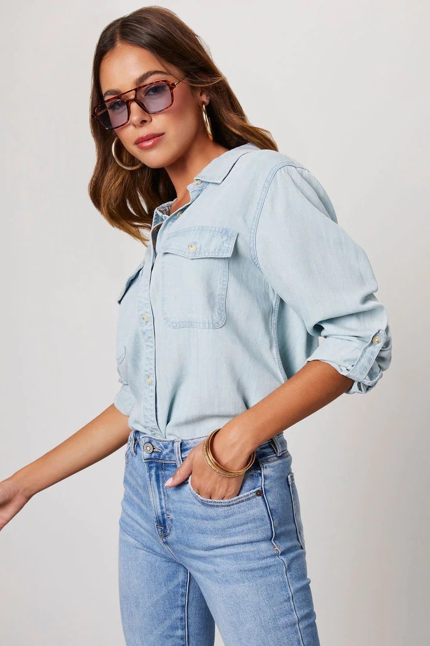 Light Blue - Women's relaxed-fit chambray button-down shirt featuring dual chest pockets and rolled sleeves, styled with denim jeans.