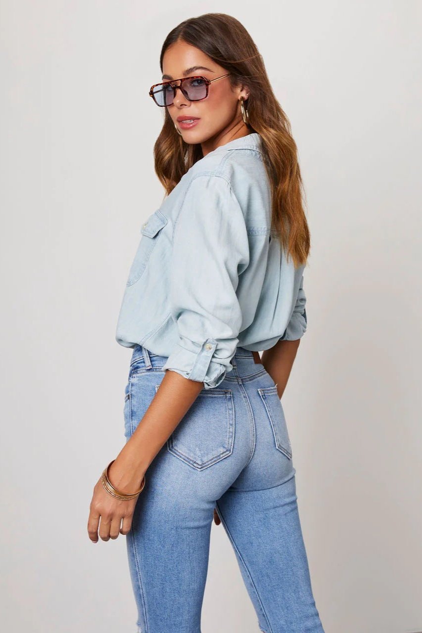 Light Blue - Women's relaxed-fit chambray button-down shirt featuring dual chest pockets and rolled sleeves, styled with denim jeans.