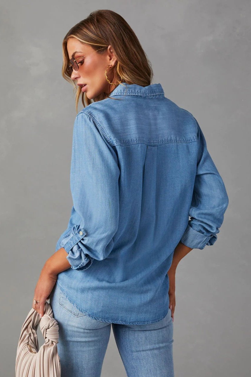 Blue - Women's relaxed-fit chambray button-down shirt featuring dual chest pockets and rolled sleeves, styled with denim jeans.