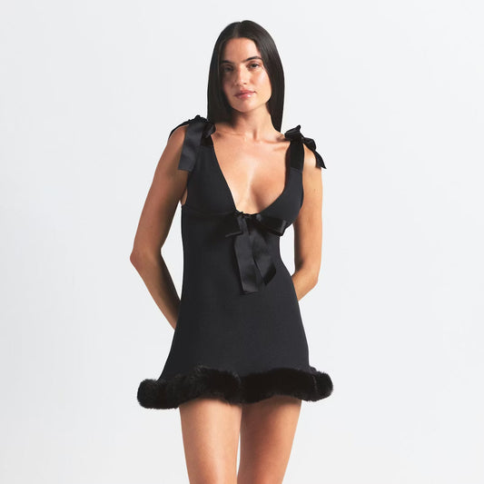 Noir - Women's black mini dress featuring a deep V-neck, satin tie-shoulder straps, a large satin bow at the bust, and a faux fur trimmed hem.