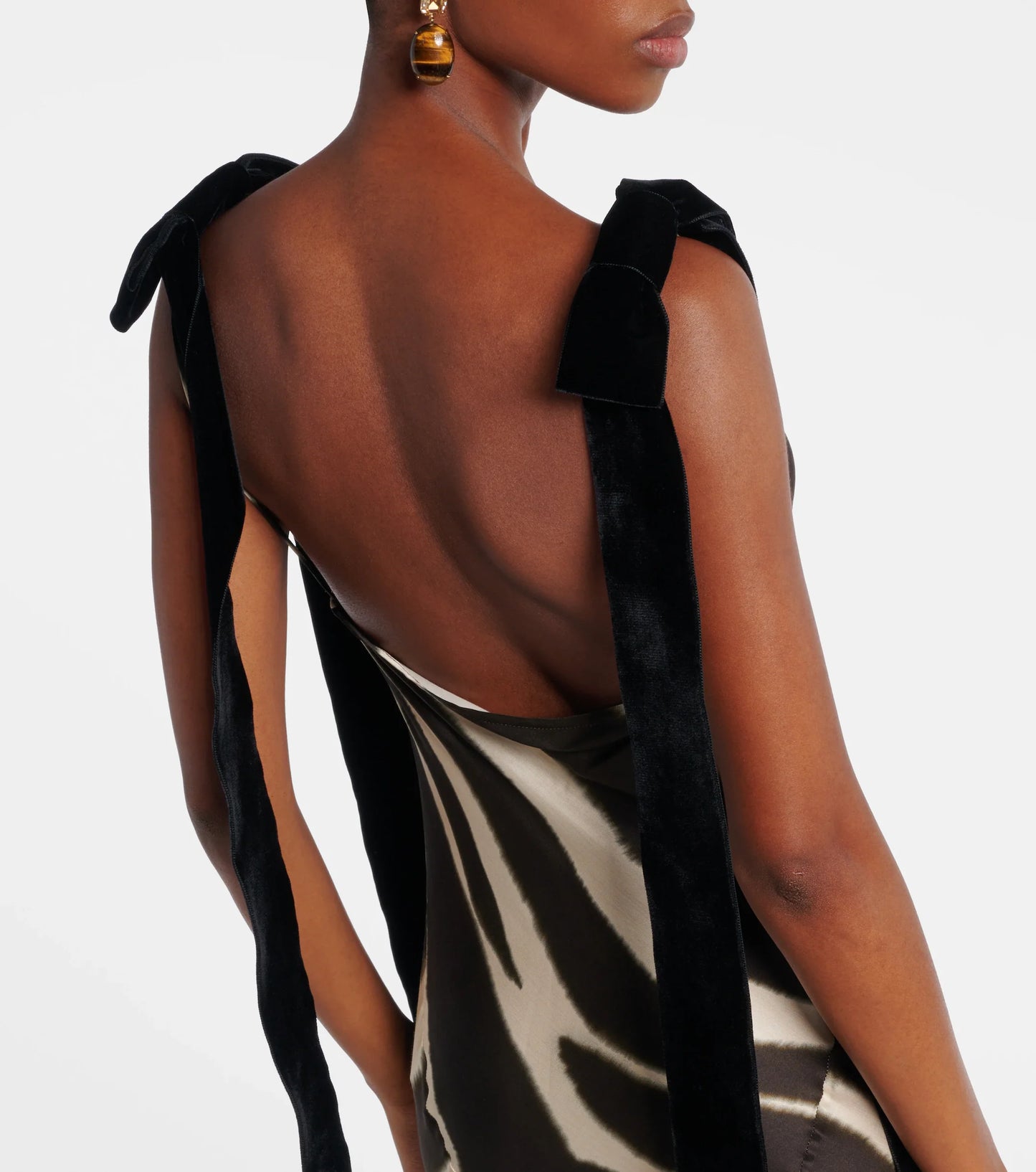 A woman modelling a floor-length, satin-look maxi dress featuring a bold, blurred zebra print and contrasting black textured shoulder ties.