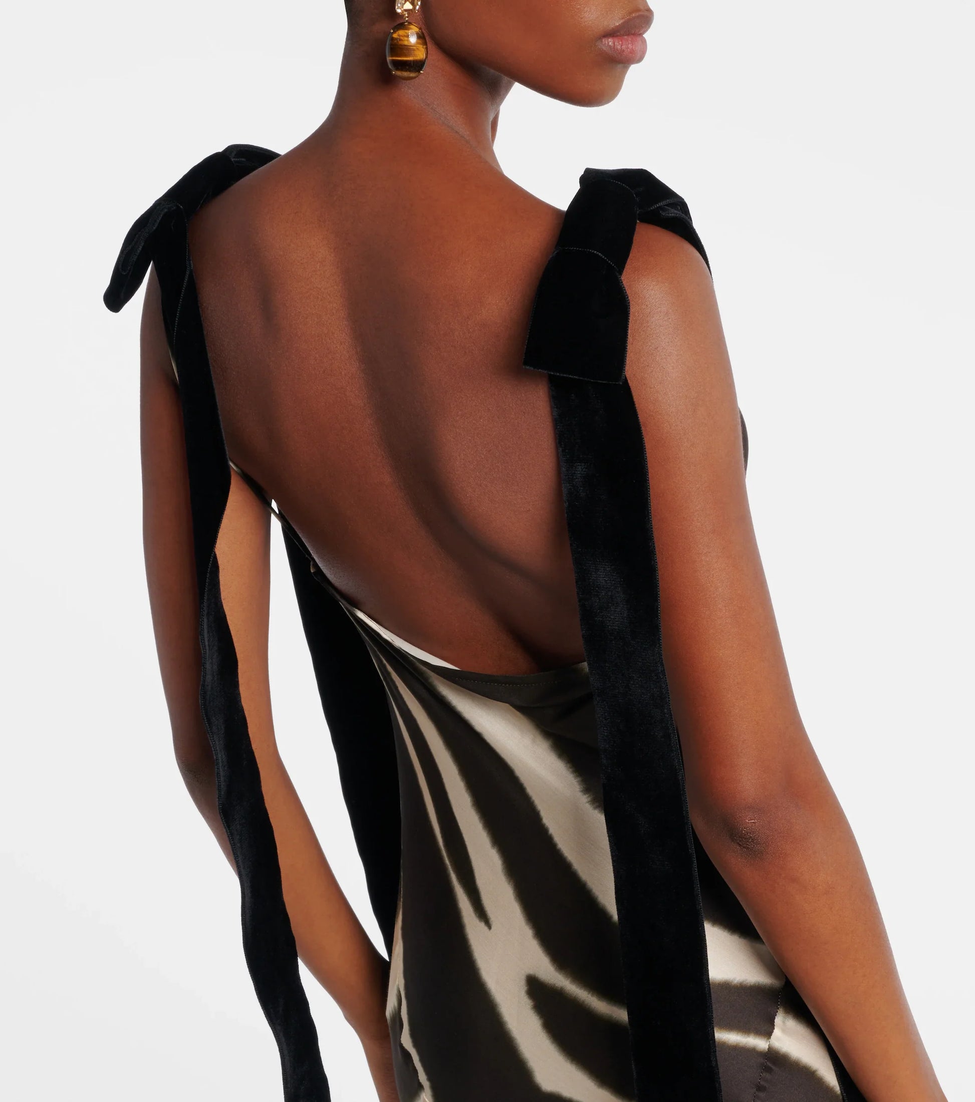 A woman modelling a floor-length, satin-look maxi dress featuring a bold, blurred zebra print and contrasting black textured shoulder ties.